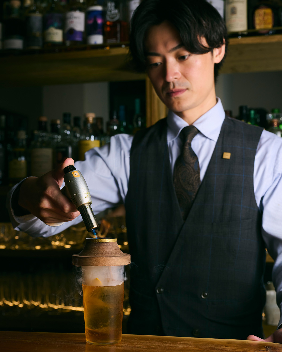 店舗のカウンターで煙頭を使った一杯を提供する様子